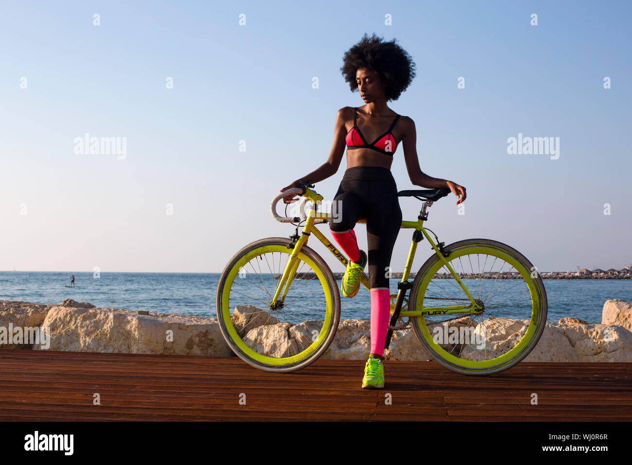 Young athletic woman in sports clothes with her road bicycle near the sea Stock Photo