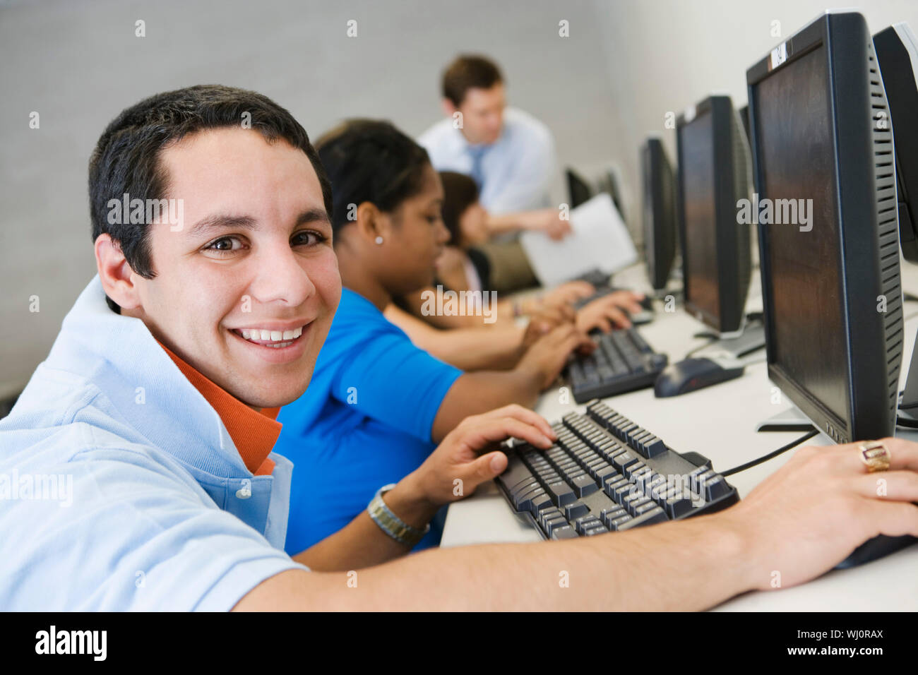 Portrait of a happy male student with classmates and professor in ...