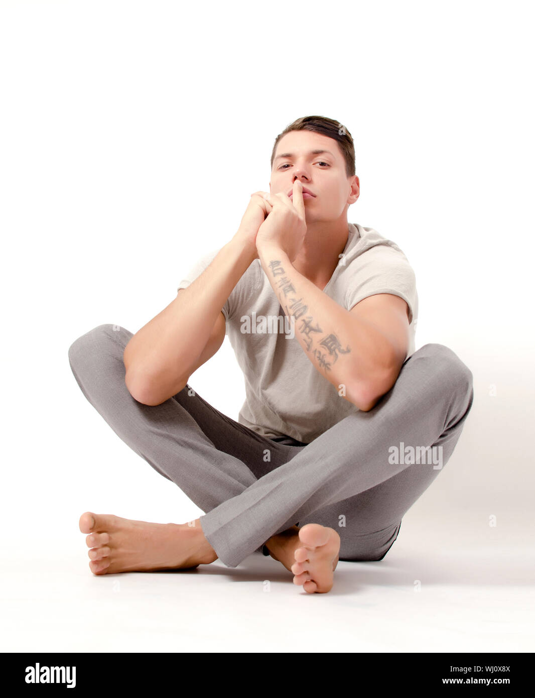 Man sitting and pointing a finger on his mouth Stock Photo