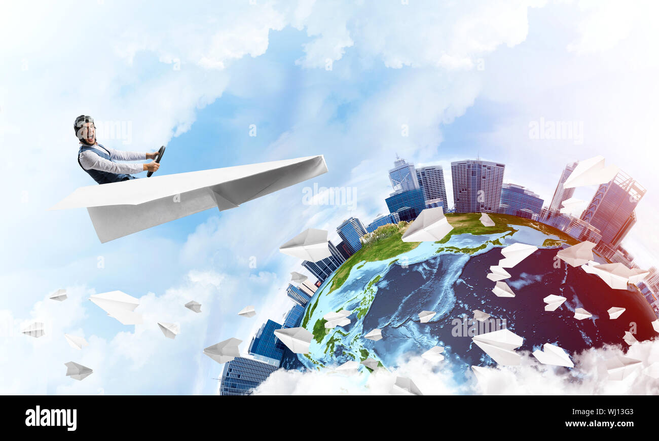 Pilot in leather helmet and goggles driving paper plane in cloudy blue ...