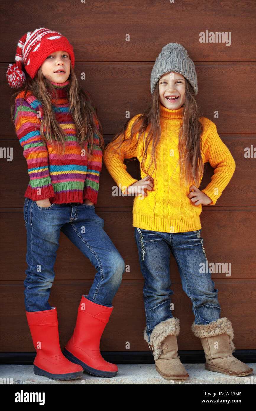 Cute little girls wearing knit winter clothes posing over wooden background Stock Photo Alamy