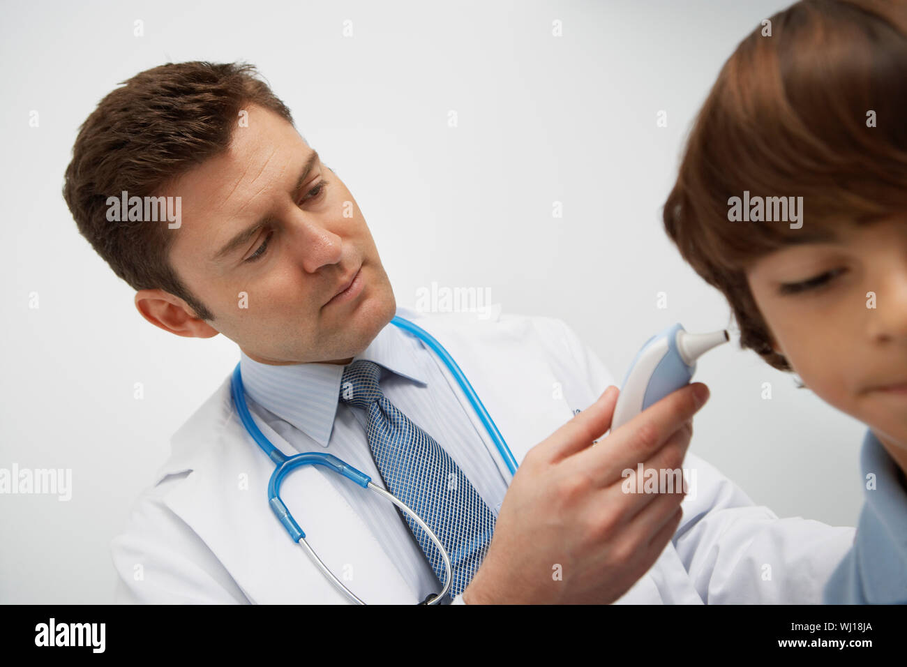 Boy having temperature taken with ear thermometer Stock Photo Alamy