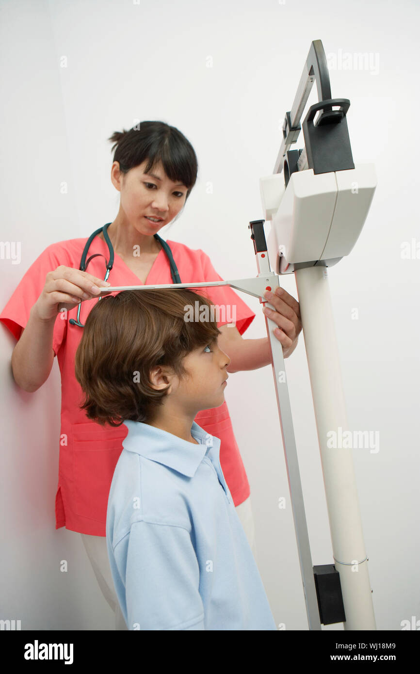 Female doctor measuring boy's height Stock Photo