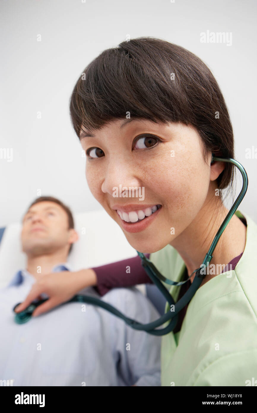 Doctor examining male patient using stethoscope in hospital Stock Photo ...