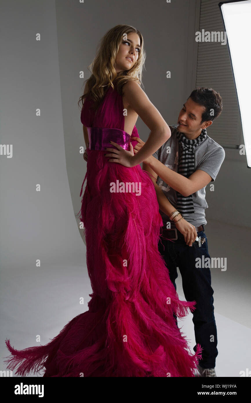 Male designer adjusting dress on a fashion model in studio Stock Photo ...