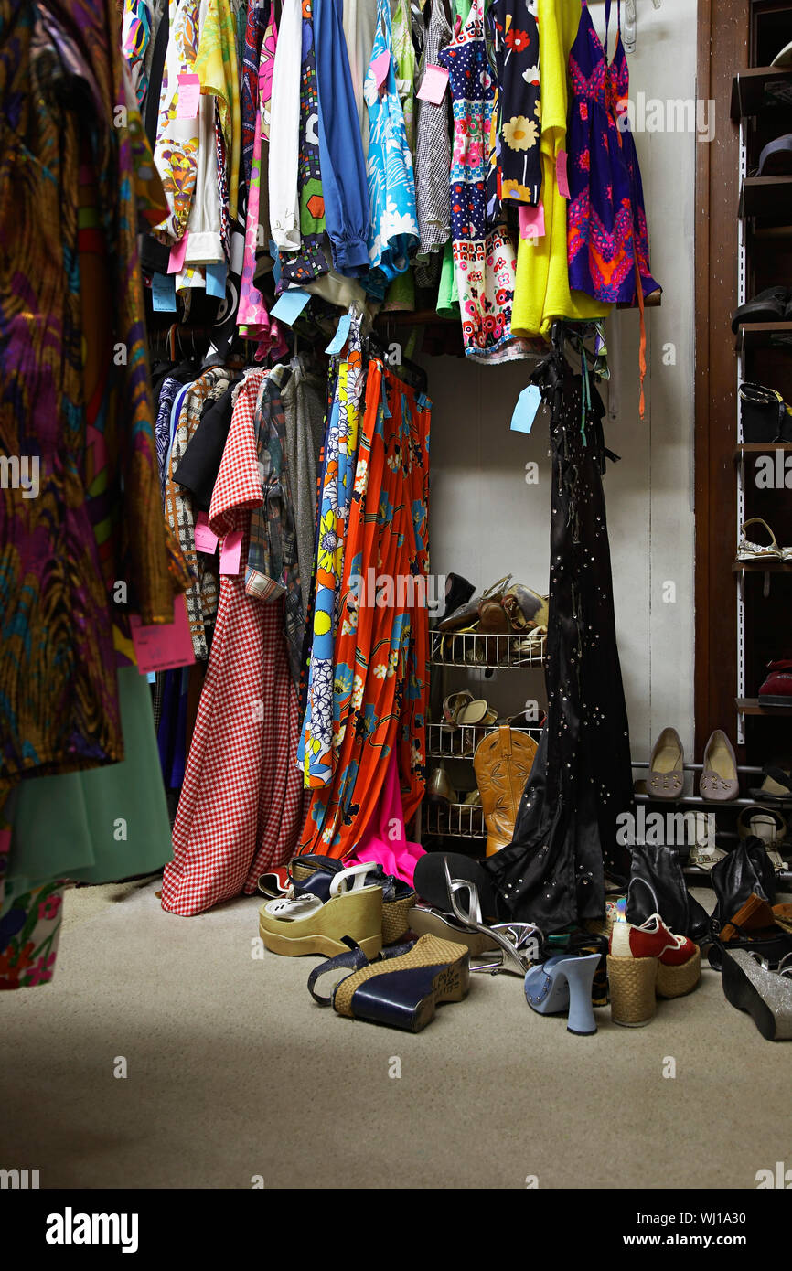 Crowded clothing racks and piled shoes in second hand store Stock Photo