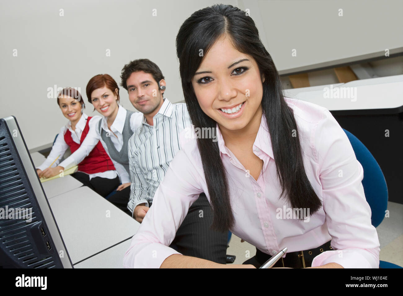 Portrait of smiling multiethnic businesspeople sitting at office desk Stock Photo