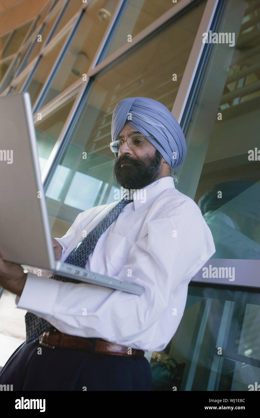 Low angle view of a serious Indian businessman using laptop Stock Photo ...
