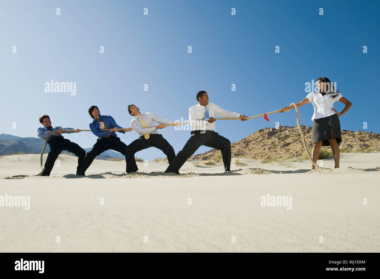 Full length of four multiethnic businessmen playing tug of war against ...