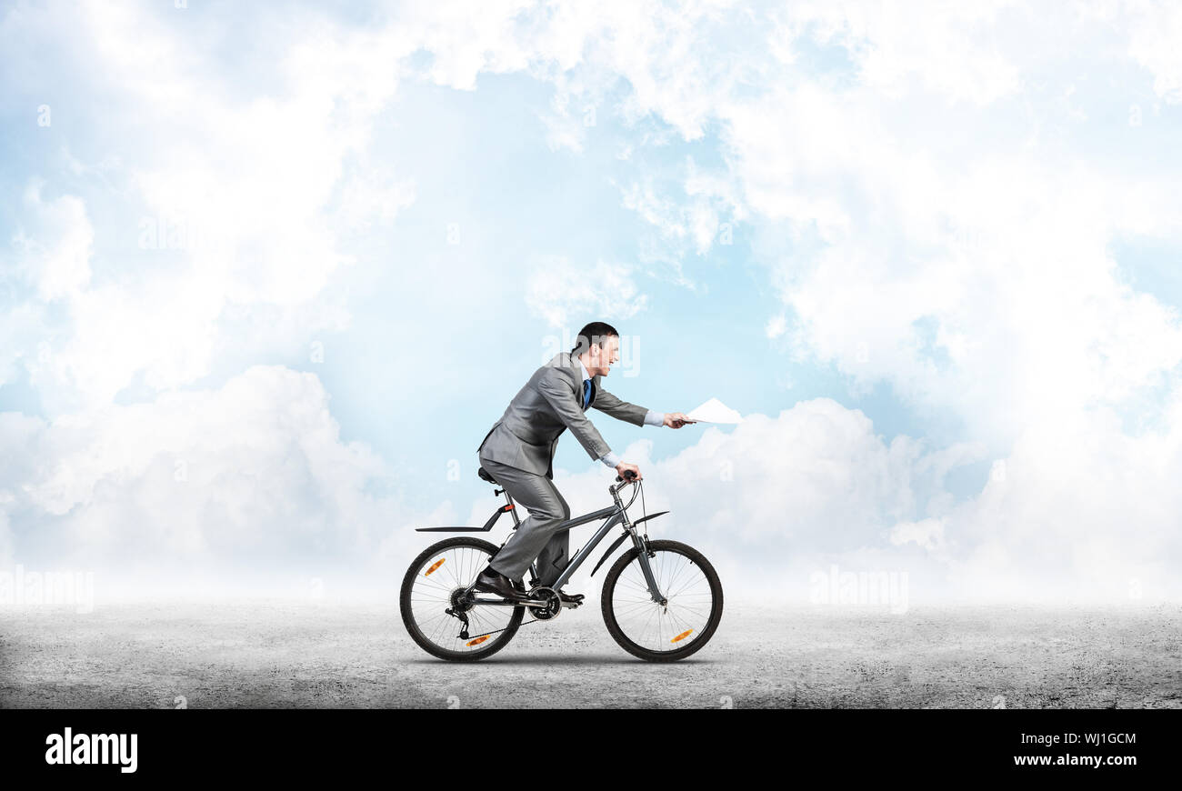 Businessman with paper documents in hand on bike. Deadline for