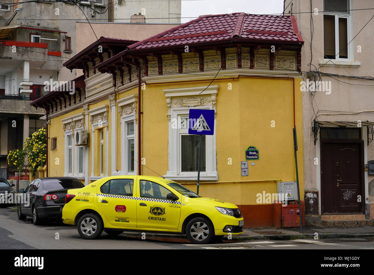 yellow taxi cab in front of a dilapidated building deterioration, Bucharest Romania Stock Photo