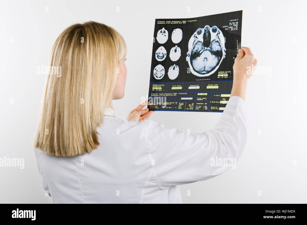 Observing Rear View Rear view of a female nurse observing x-ray report isolated over white ...