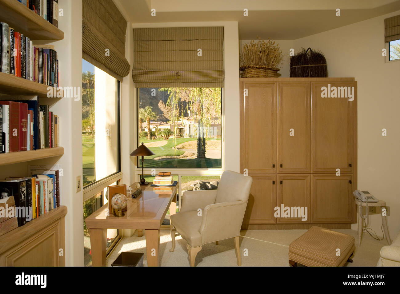View of bookshelf by chair and table in study room Stock Photo - Alamy