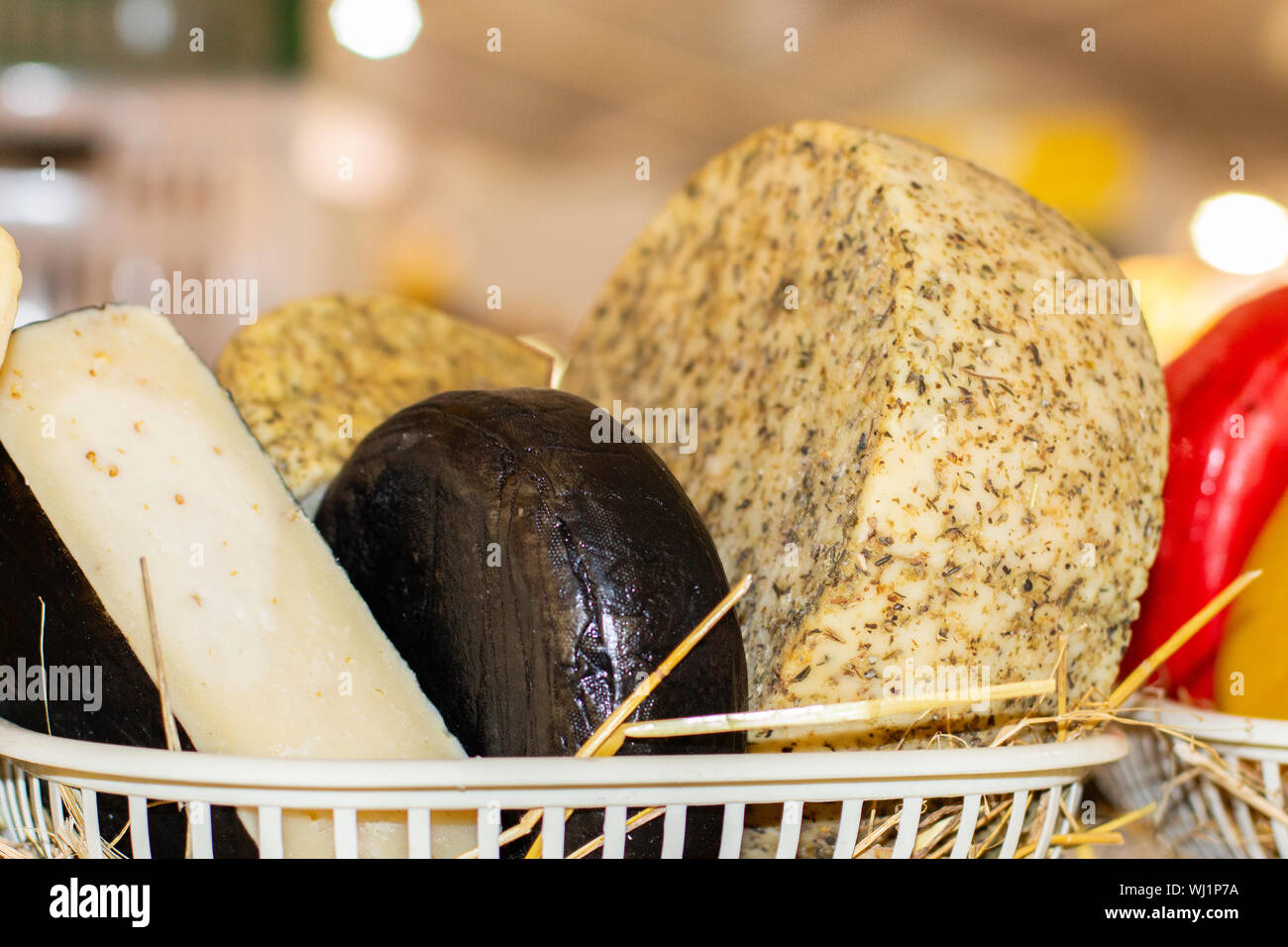 Different varieties of cheese in a basket on a farm counter. Round