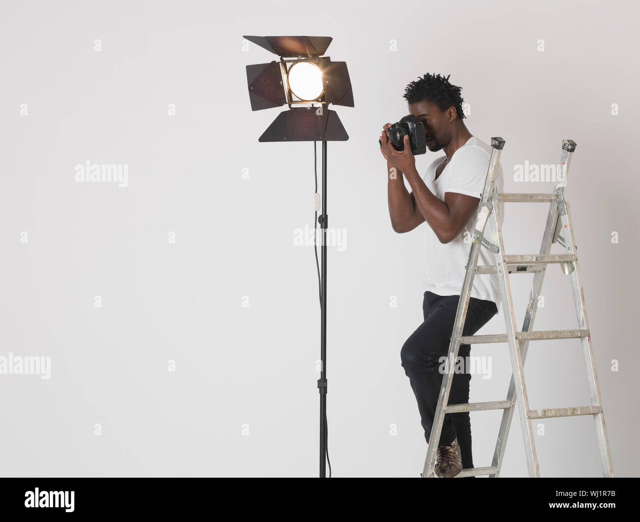Male photographer taking photos with camera in studio Stock Photo