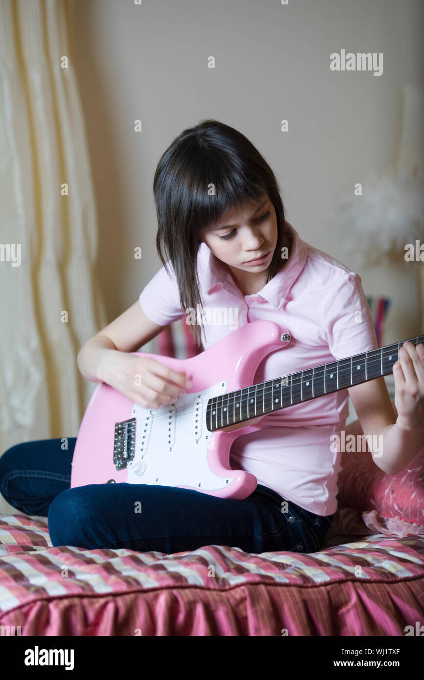 Young girl playing electric guitar on bed at home Stock Photo - Alamy