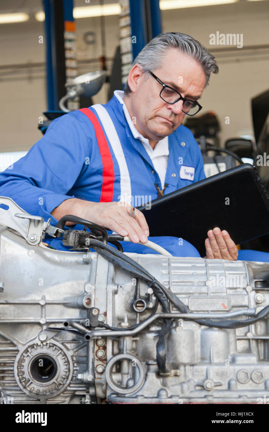 Senior mechanic analyzing car engine and holding clipboard Stock Photo ...
