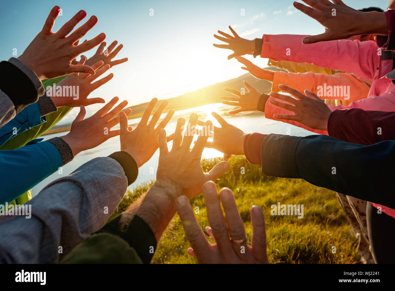 Hands of many friends reaching together for the sun. Friendship or travel concept Stock Photo