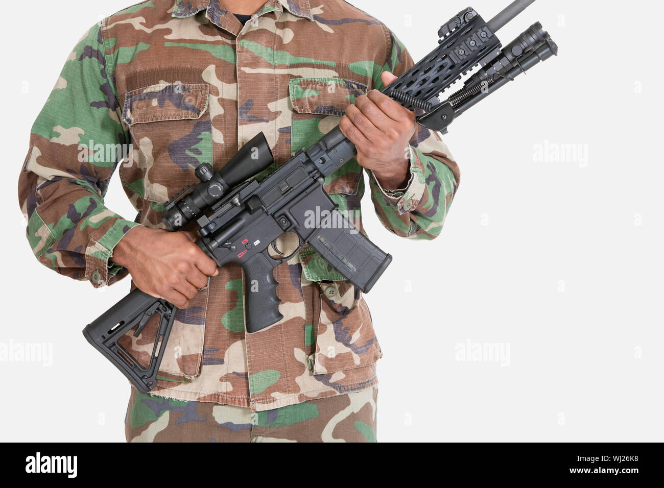 Midsection of US Marine Corps soldier holding M4 assault rifle over gray background Stock Photo