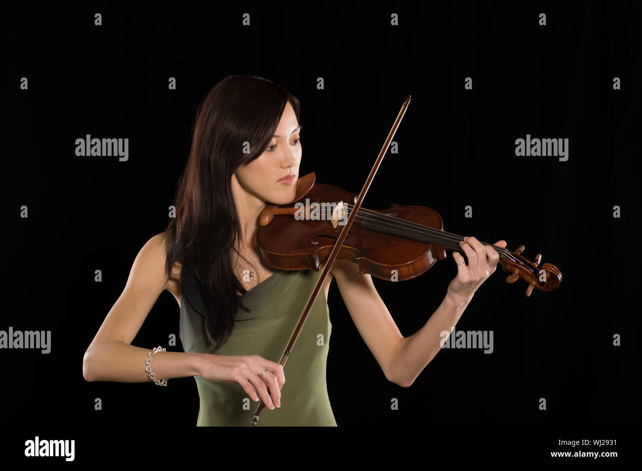 Beautiful young female playing violin isolated over black background ...