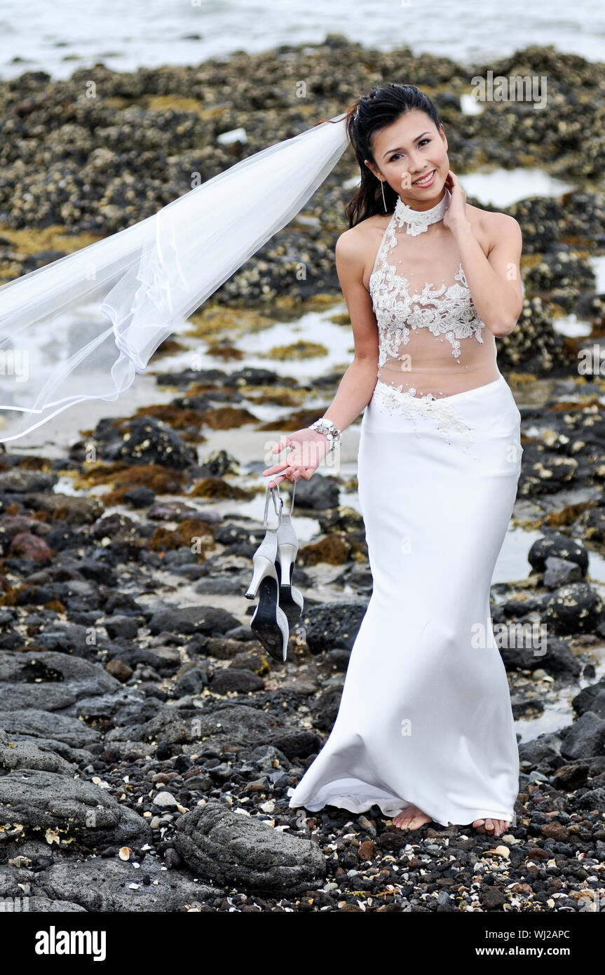 Full Length Portrait Of Smiling Bride Holding High Heels While Standing