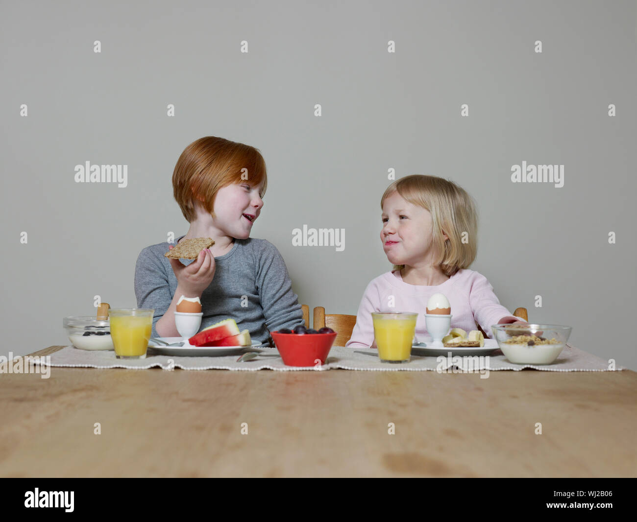 Two smiling sisters talking while eating breakfast together Stock Photo ...