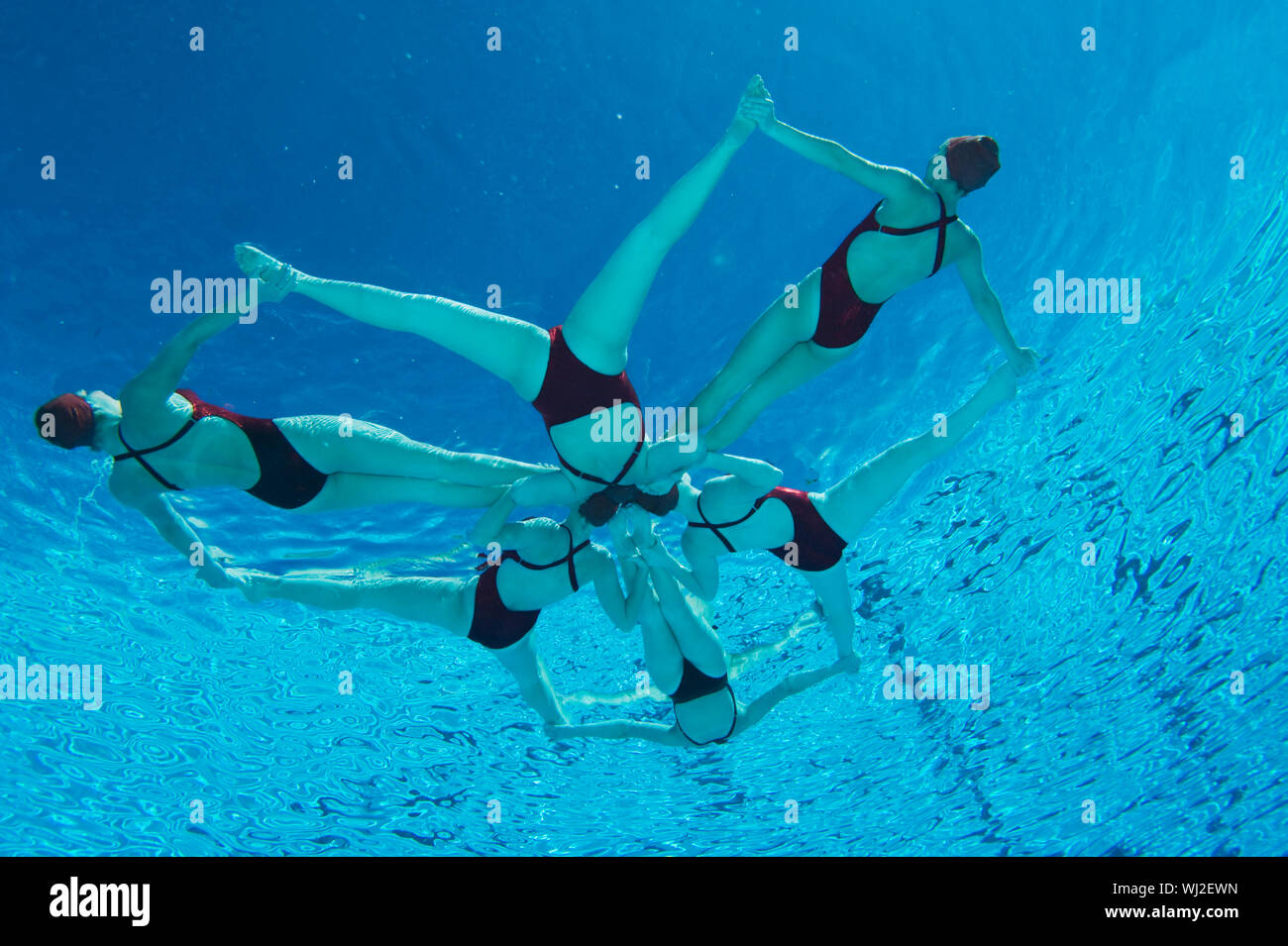 Underwater view of synchronized swimmers forming a star shape in pool Stock Photo