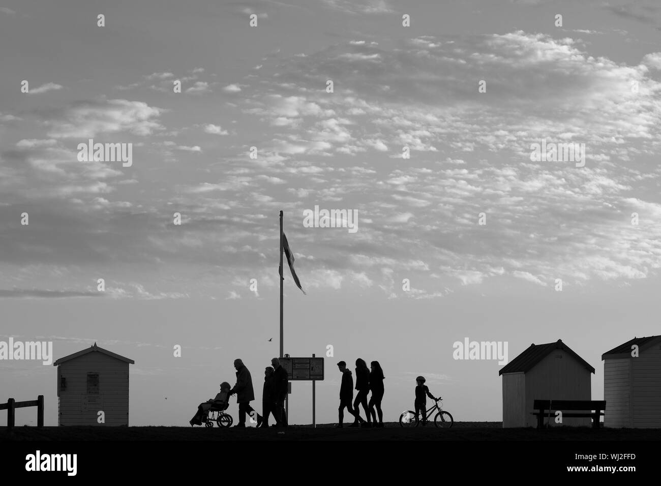 Silhouette People Walking On Street Against Cloudy Sky Stock Photo