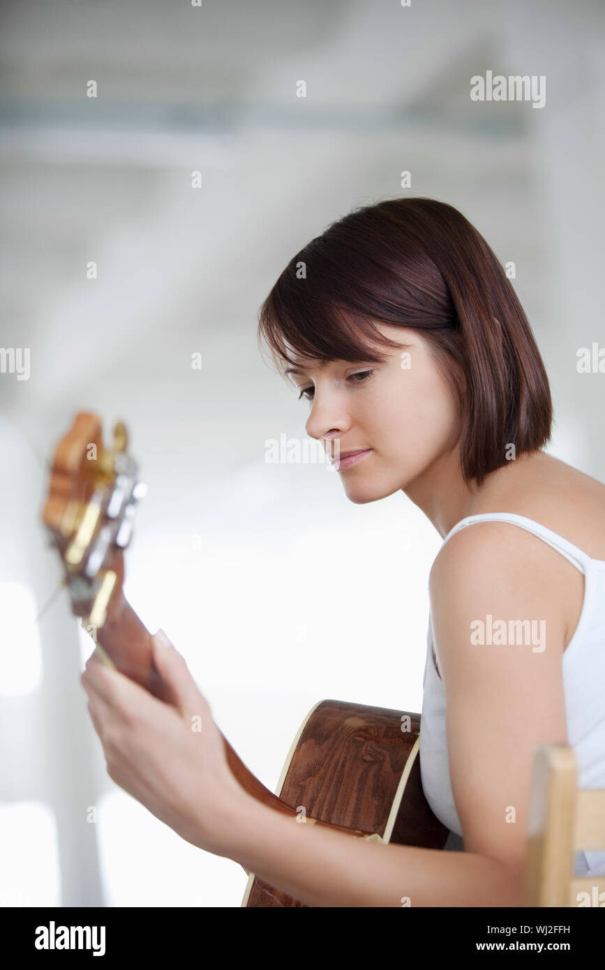 Beautiful young woman playing an acoustic guitar in warehouse Stock ...
