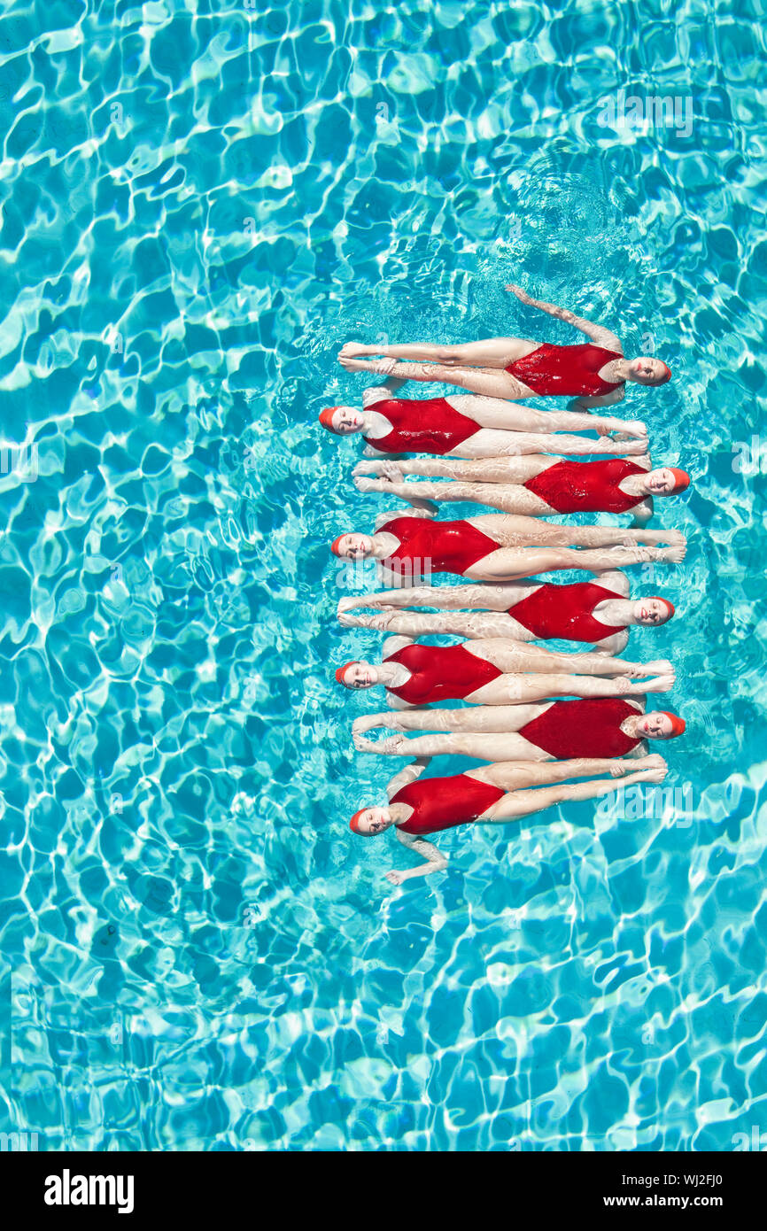 Group of swimmers performing synchronized swimming in pool Stock Photo ...