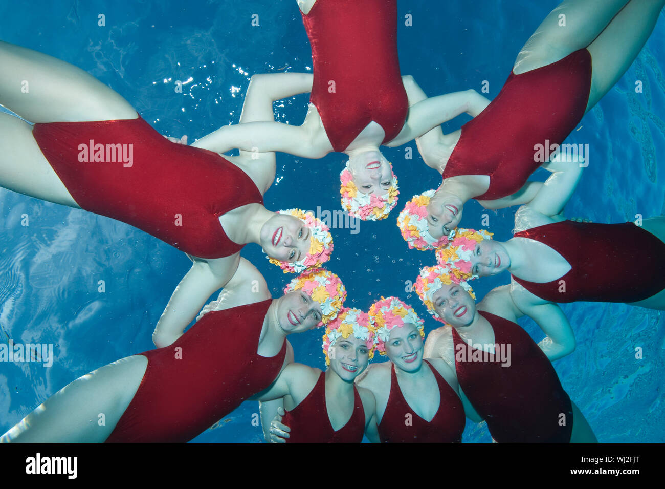 Underwater view of happy synchronized swimmers performing in pool Stock Photo
