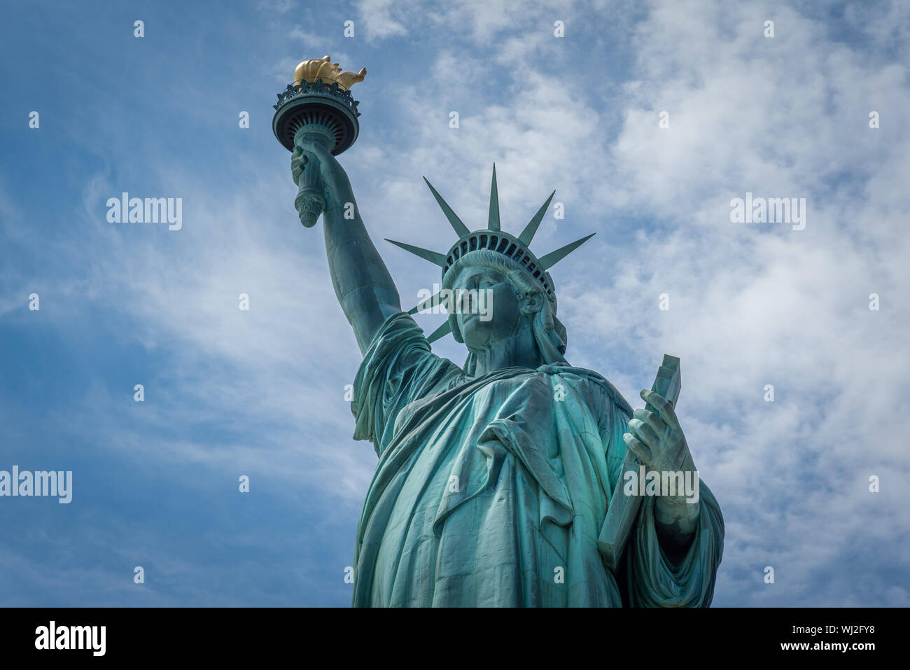 Shot of the Statue of Liberty in New York City, Usa. The shot is taken during a beautiful sunny day with a blue sky and white clouds in the background Stock Photo
