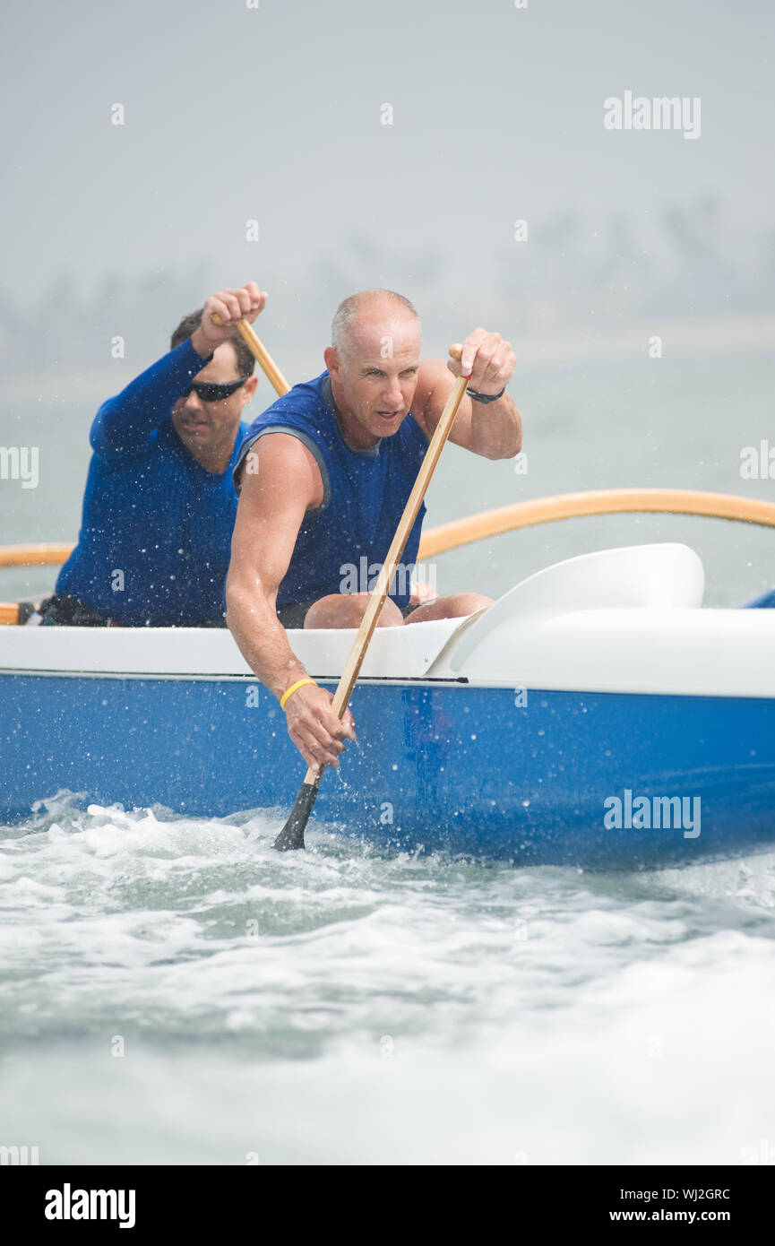 Two male rowers paddling outrigger canoe in race Stock Photo