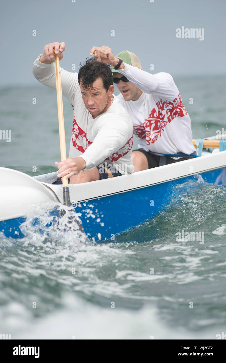 Confident male rowers paddling outrigger canoe in race Stock Photo
