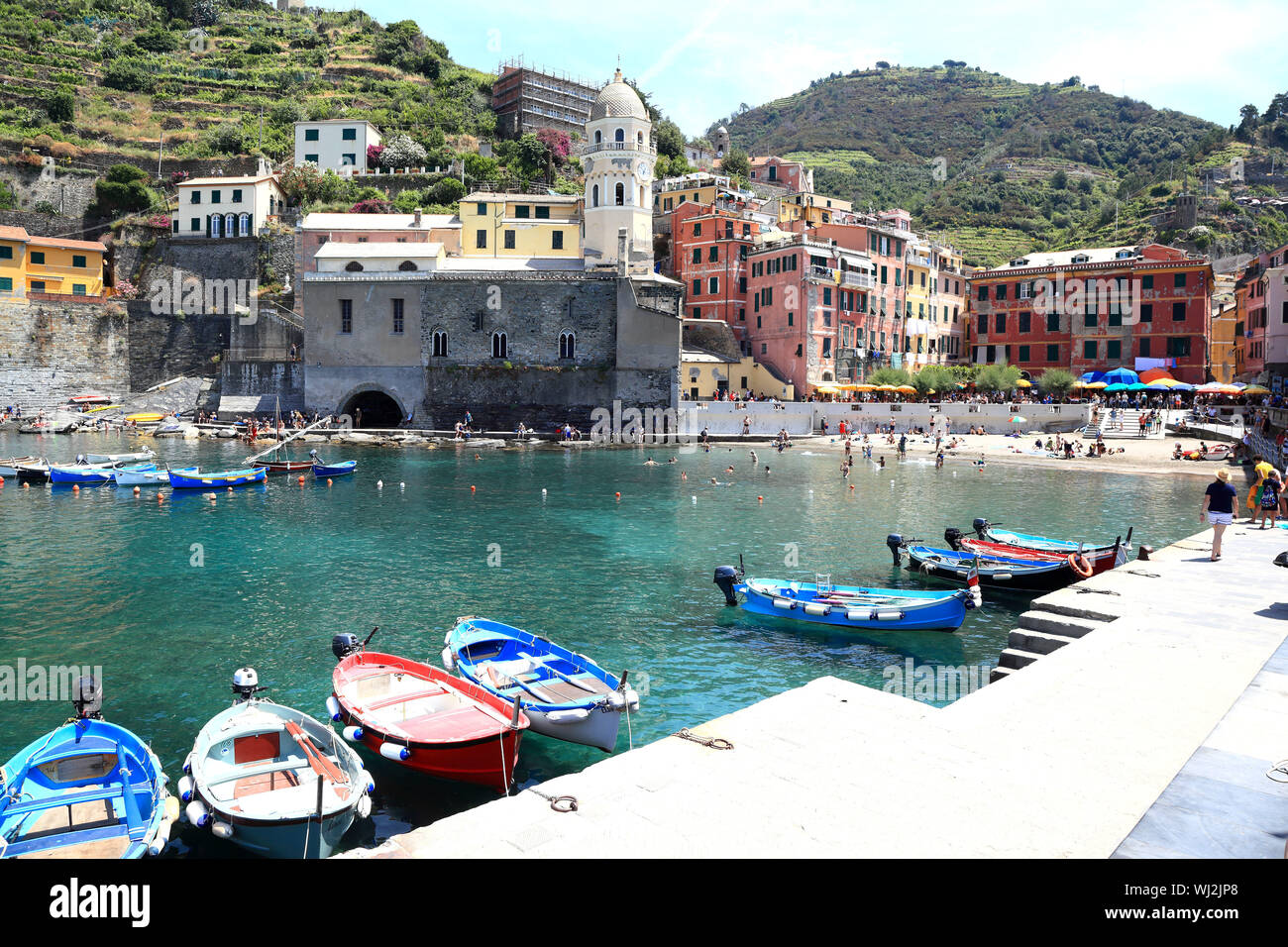 Editorial Image: Vernazza, Cinque Terre / Italy - june 21 2019: Tourists swim and stroll around the beach and harbor of the colourful historic town. Stock Photo