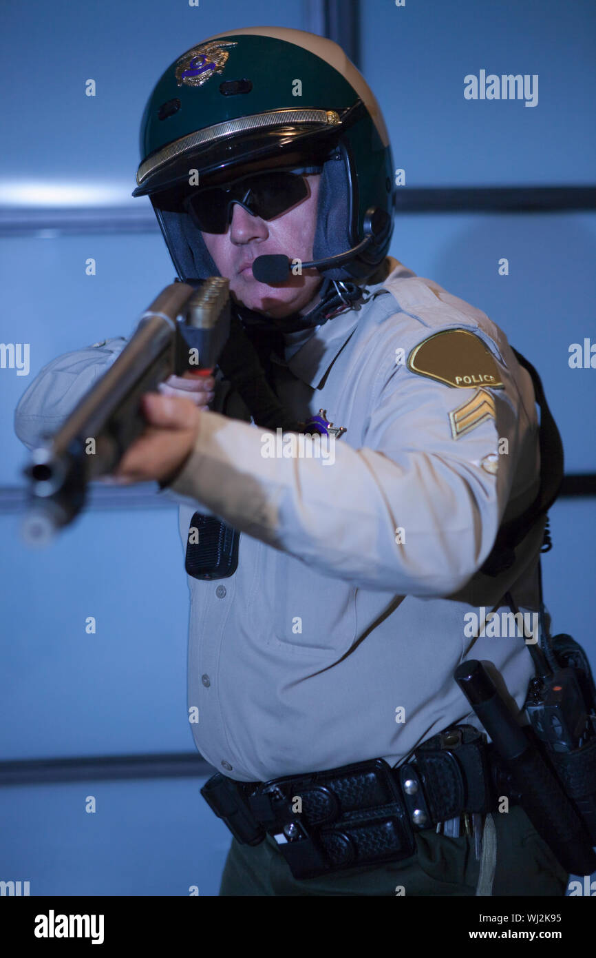Middle aged traffic cop aiming rifle against door Stock Photo - Alamy