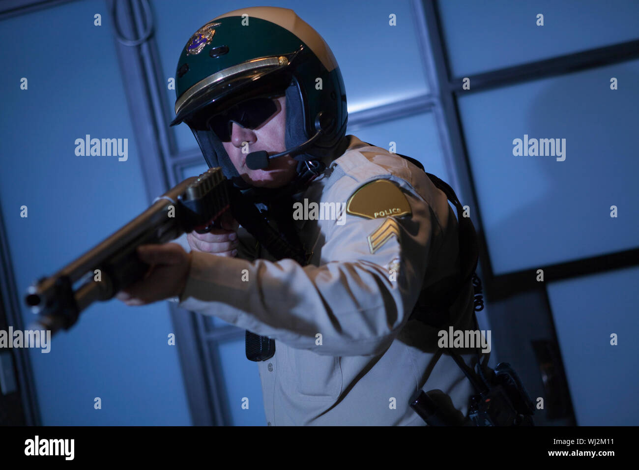 Middle aged traffic cop aiming rifle against door Stock Photo - Alamy