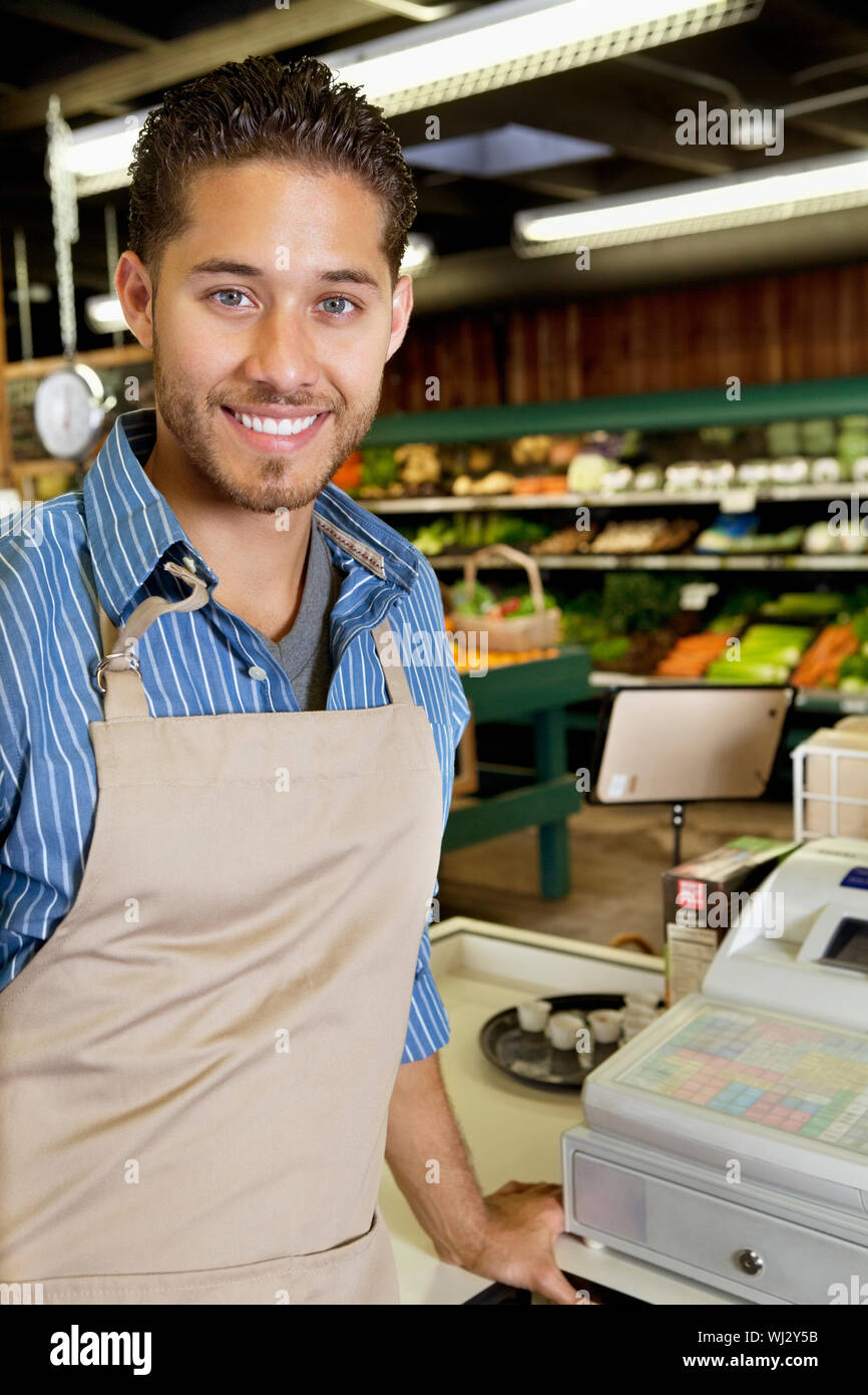 Portrait of handsome store employee standing near cash register in