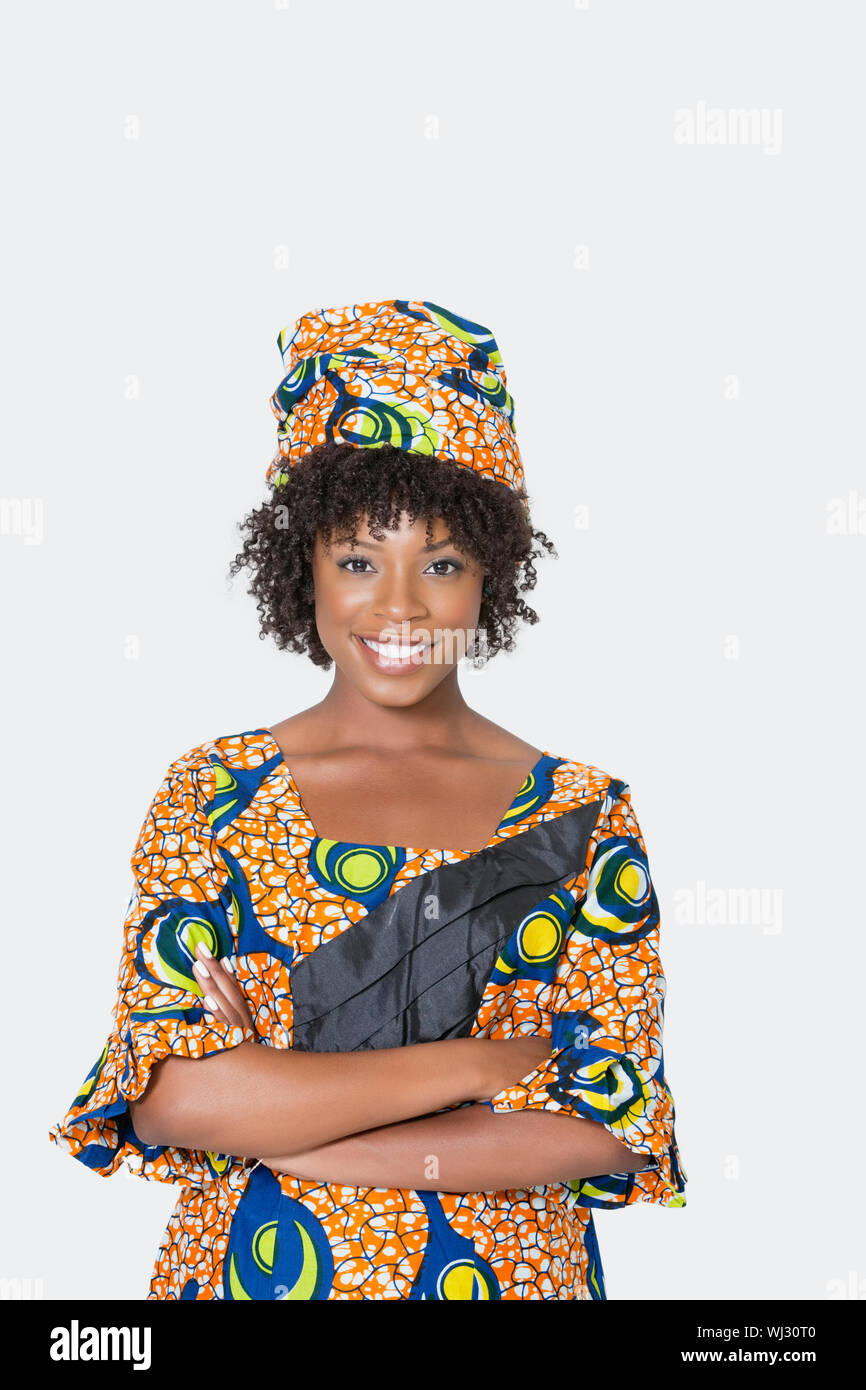 Portrait of young woman in African print attire standing arms crossed ...