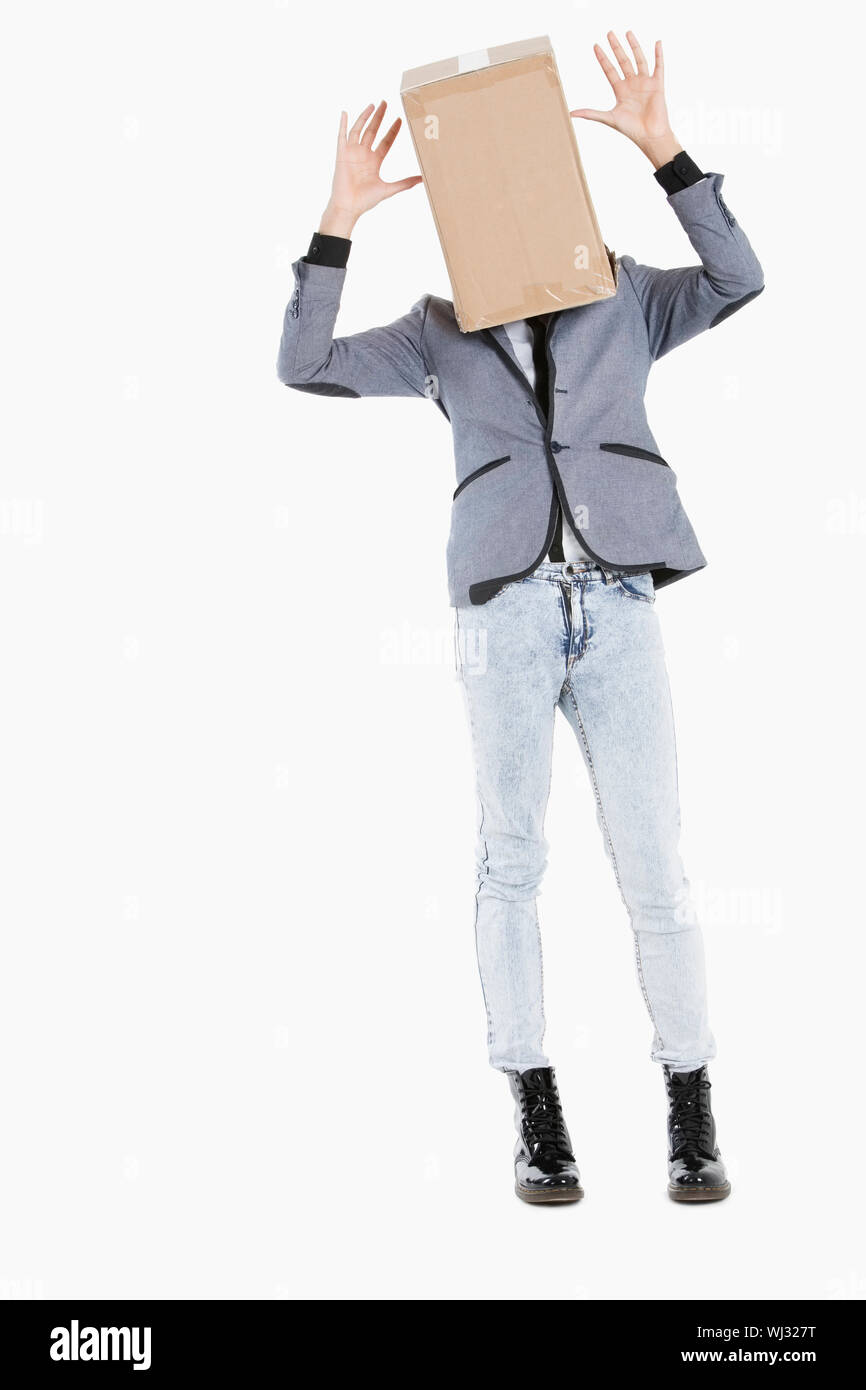 Young boy with box covered over his face and hands raised over gray ...