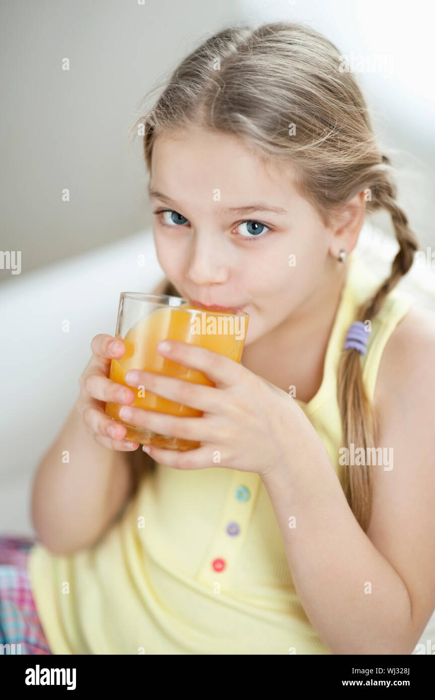 Portrait of little girl drinking orange juice Stock Photo - Alamy