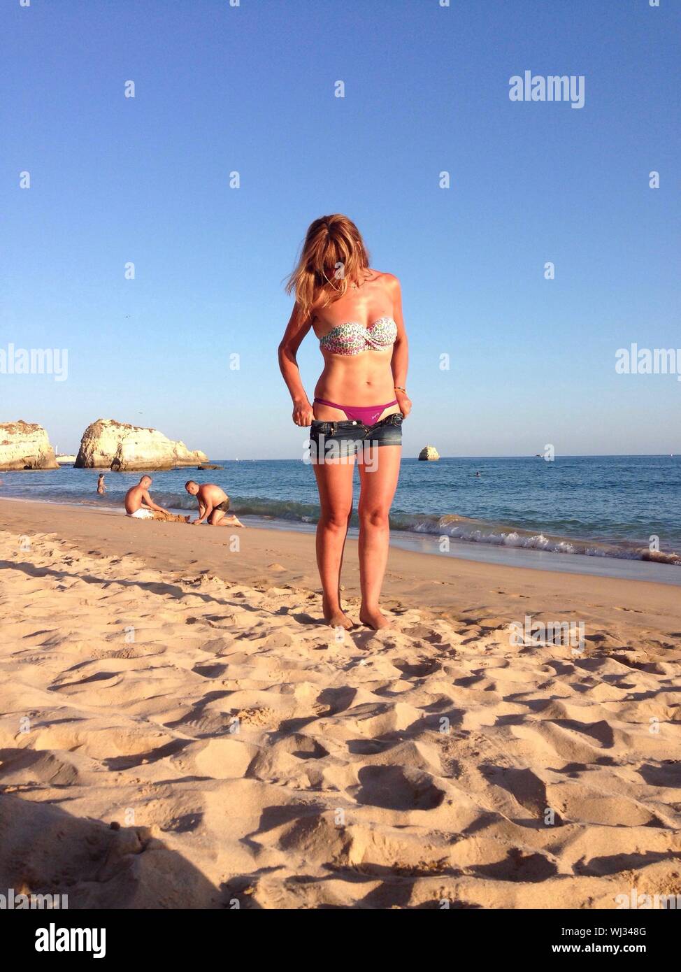Woman Wearing Hot Pants Standing On Shore At Beach Against Sky Stock Photo  - Alamy