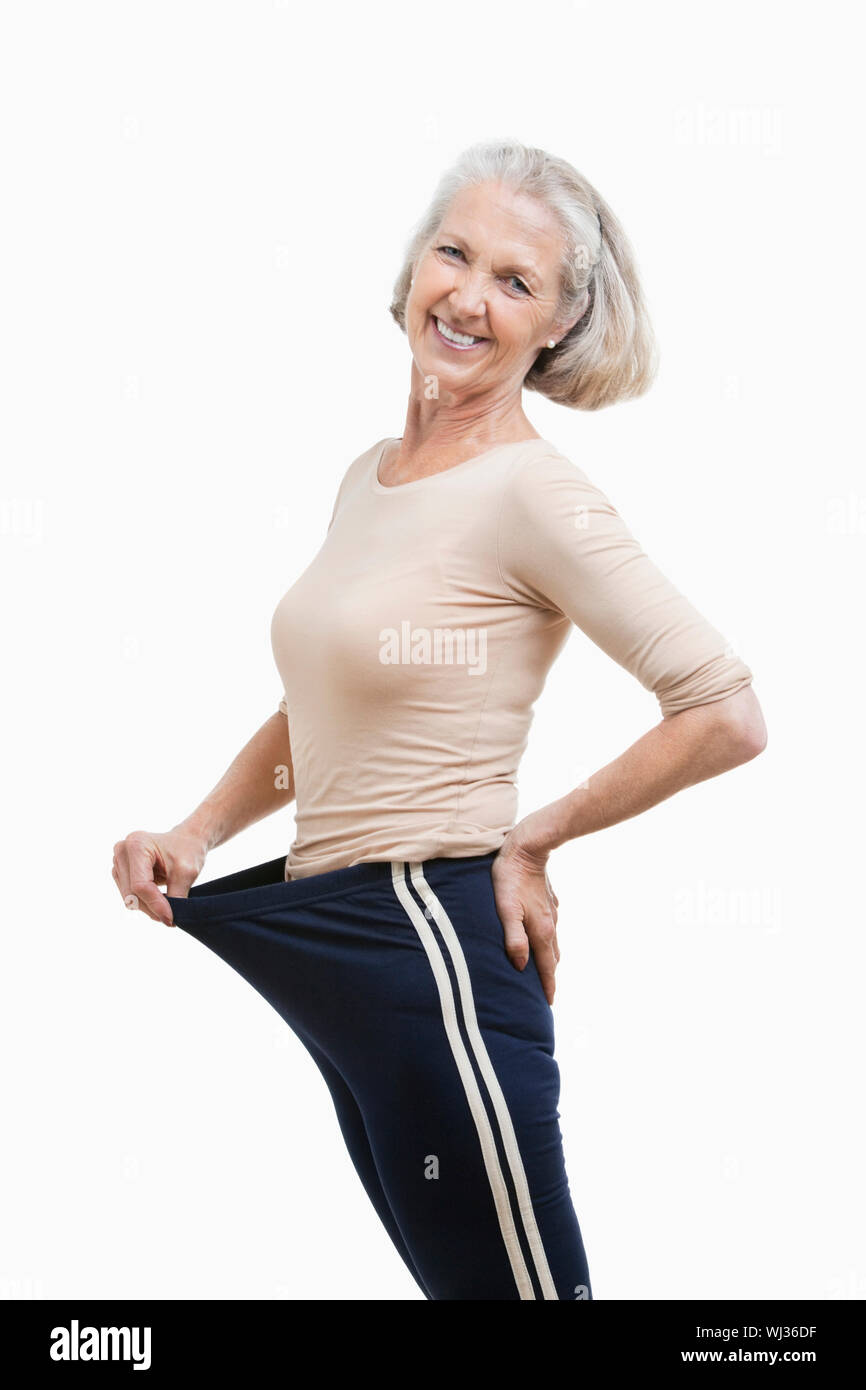 Portrait of senior woman in oversized pants against white background