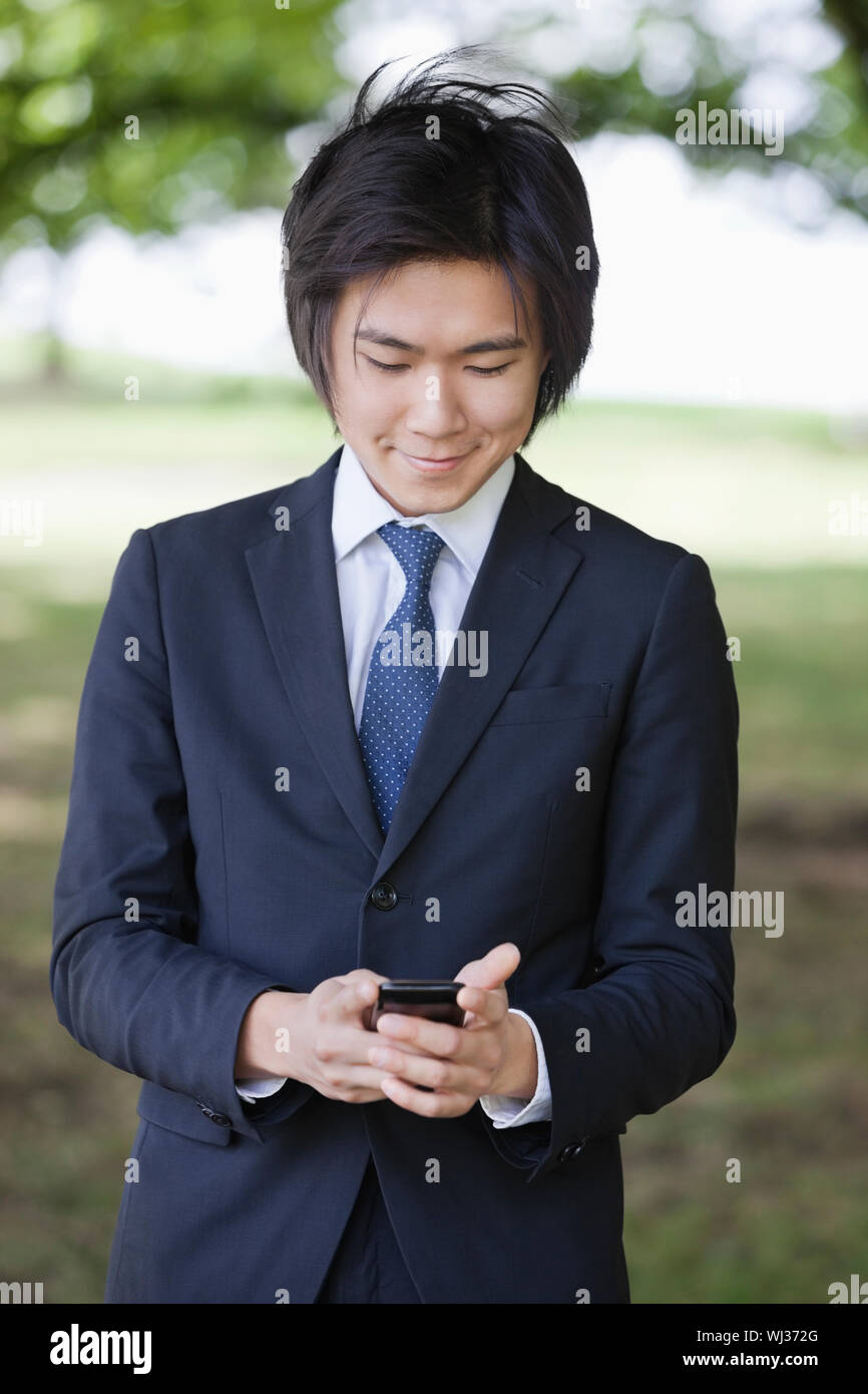 Young businessman using cell phone at park Stock Photo