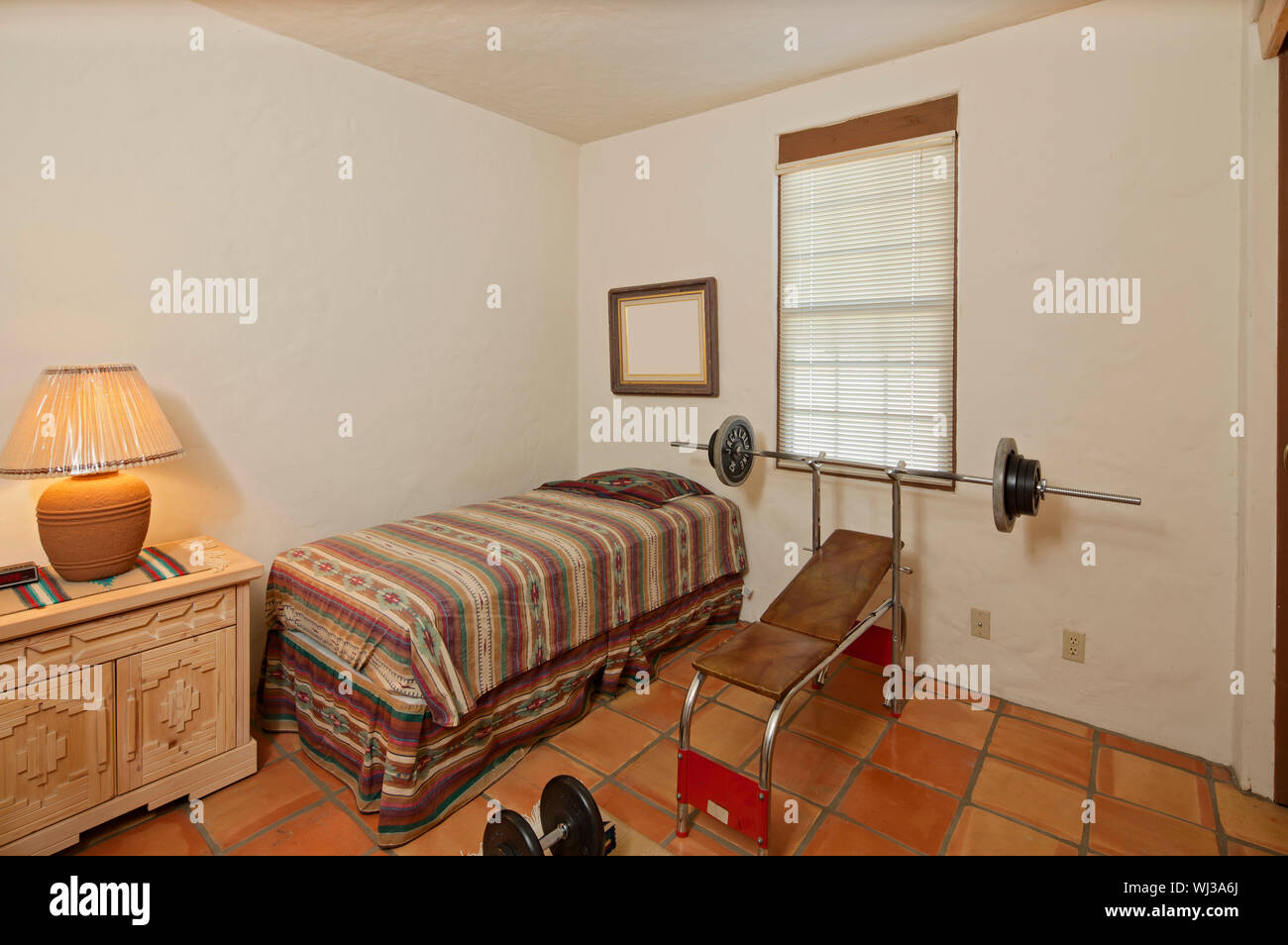 Small single bedroom with bench press and weights Stock Photo Alamy