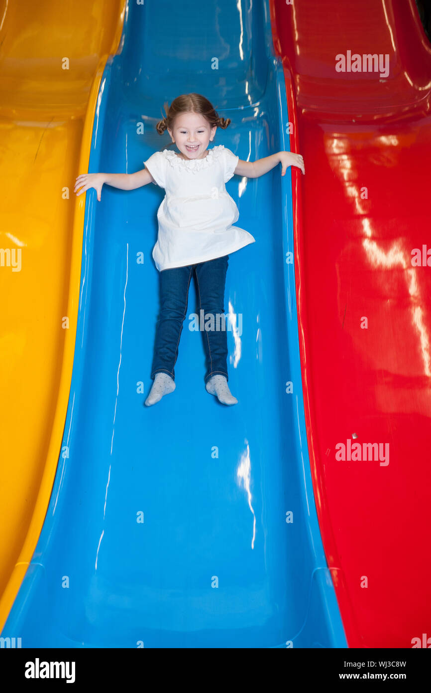 Young girl slides down colorful slide Stock Photo Alamy