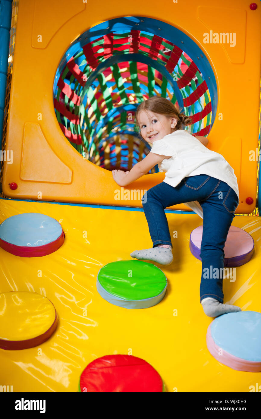 Young girl climbing up ramp into tunnel at soft play centre Stock Photo ...