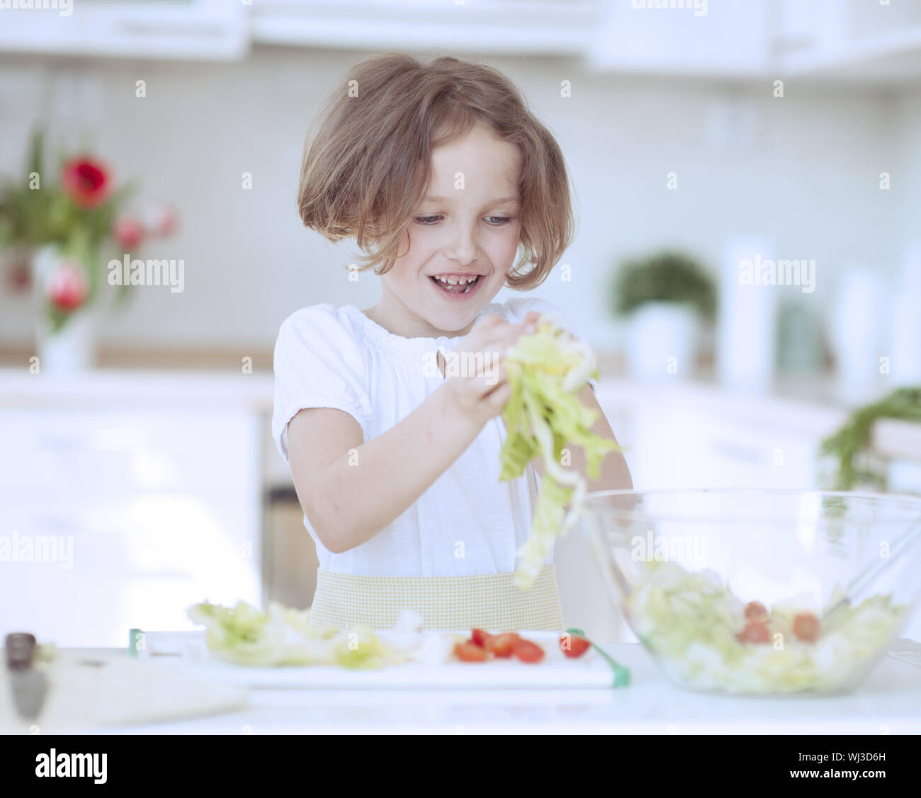 Young girl placing lettuce in salad bowl Stock Photo