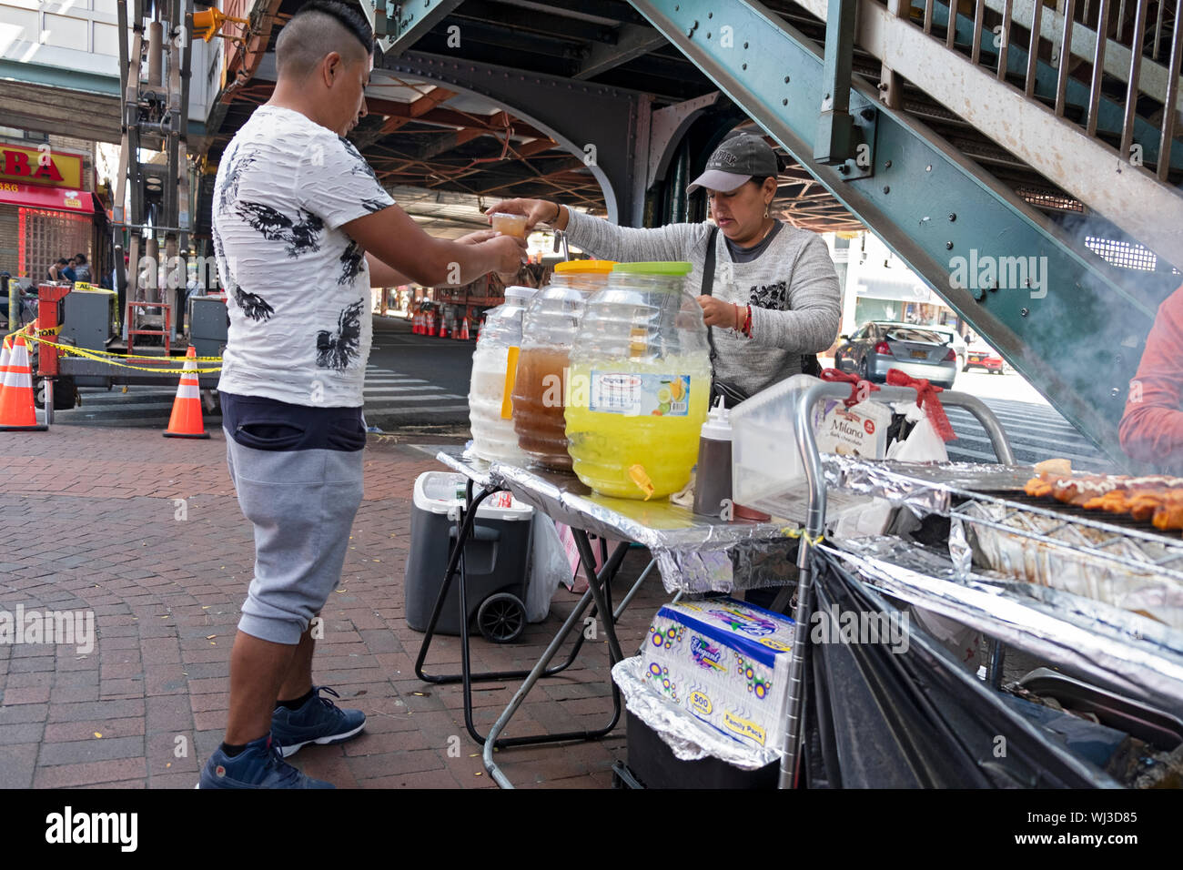 A woman selling cold drinks on a late summer day under the elevated subway in Jackson Heights, Queens, New York City. Stock Photo