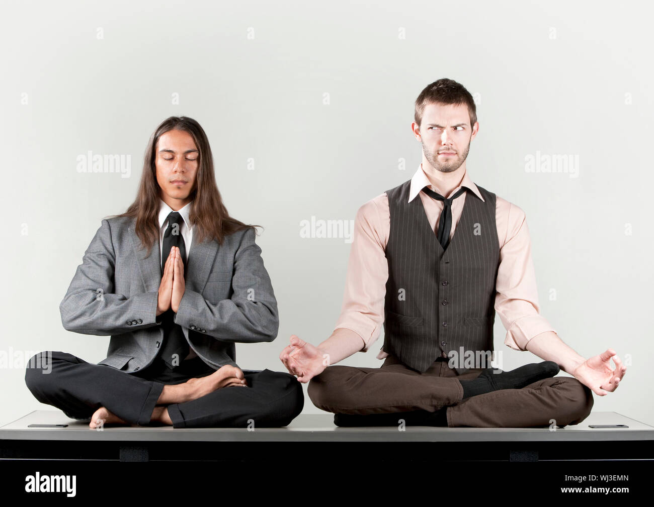 Two businessmen meditating on their office desk Stock Photo - Alamy